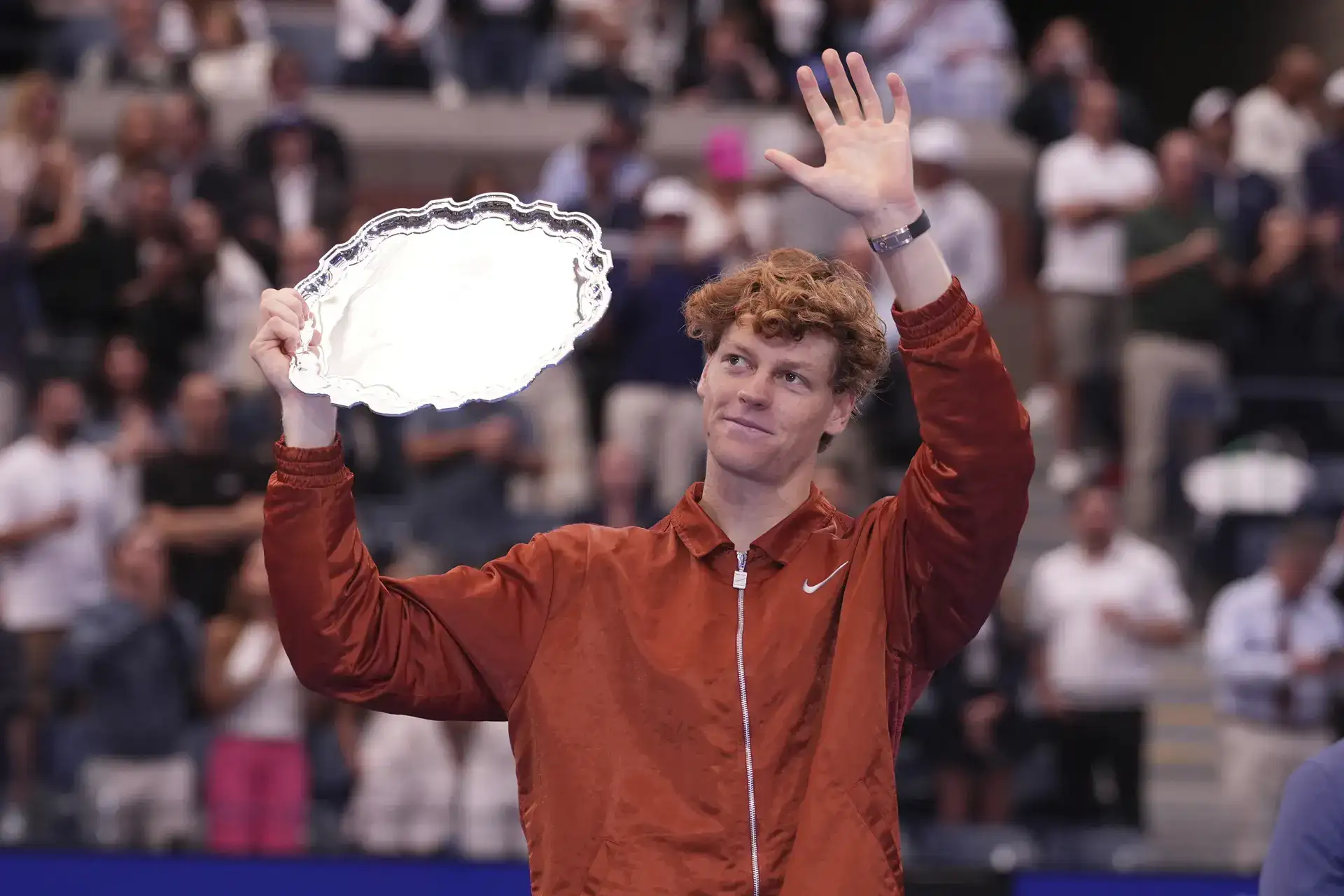 Carlos Alcaraz holds the championship trophy as Jannik Sinner looks