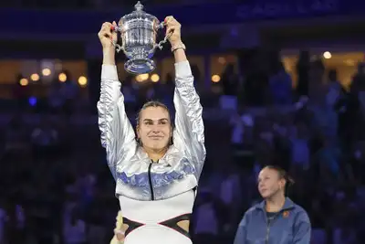 Aryna Sabalenka holds up the championship trophy after defeating Amanda Anisimova