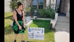 Sara Gonzales puts a 'Nagarjuna is an H-1B trafficker' poster in the lawn of the owner of an IT