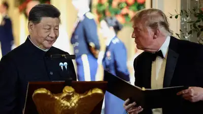US President Donald Trump holds a binder as he stands next to Chinese President Xi Jinping