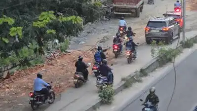 Motorists navigate through pothole debris filled road in front of the FTI campus near