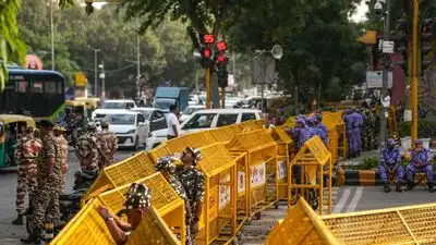 Security personnel stand guard behind multi-layered police barricades set up near Janpath metro