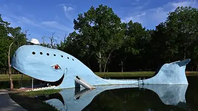 Beside a quiet pond in Oklahoma, an enormous blue whale rises from the grass, and travellers