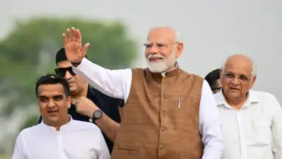 Prime Minister Narendra Modi waves towards supporters during a roadshow in Banaskantha