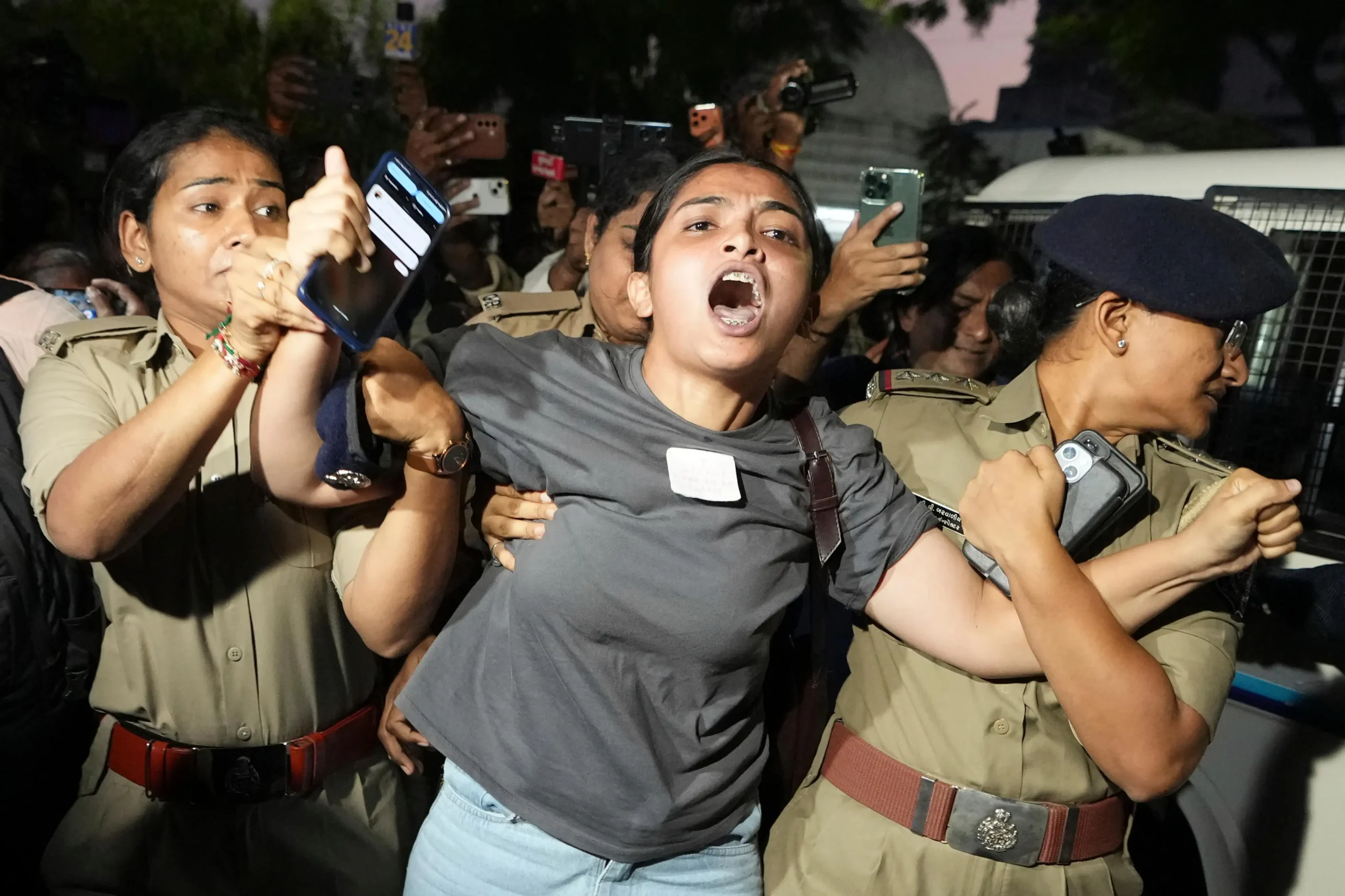 10, 2026 A man climb on a police vehicle is detained by police during a protest demanding